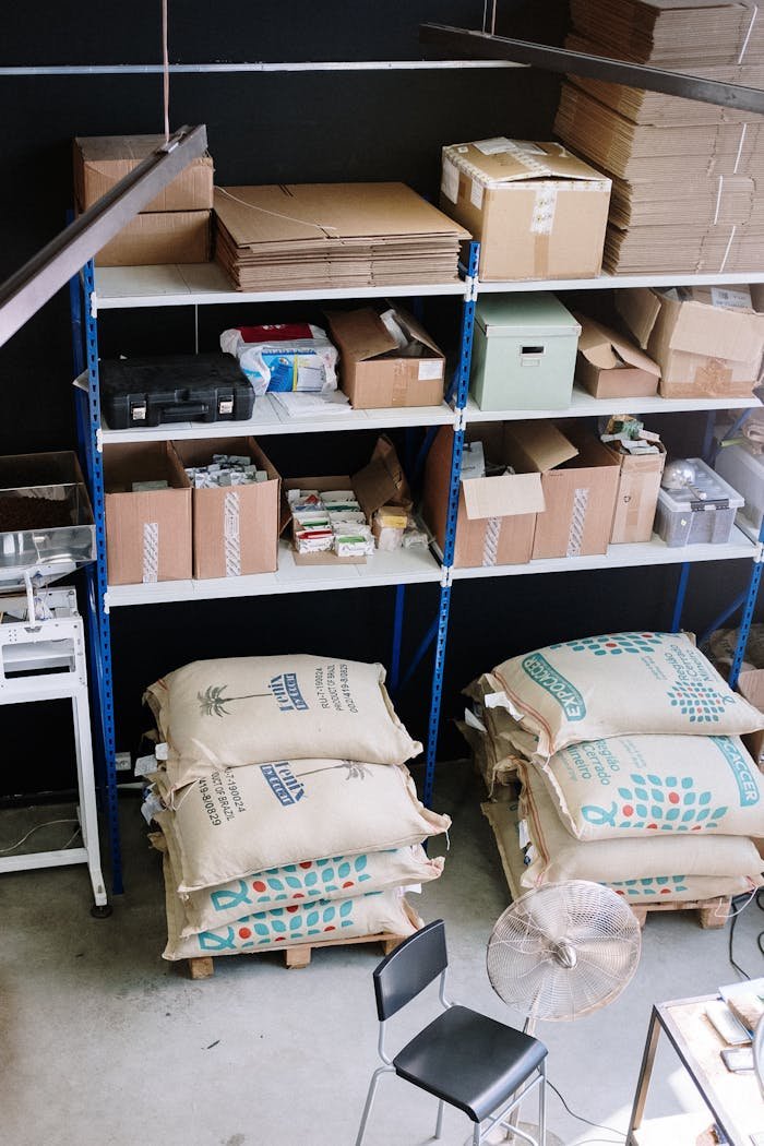 Organized warehouse with shelves filled with supplies and large sacks stored below.